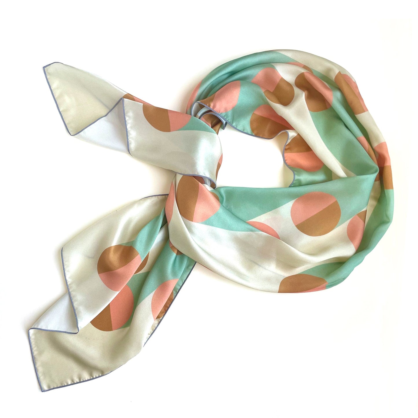 Art deco inspired geometric print on a long silk scarf in subtle pastels: pink, grey, and gold.