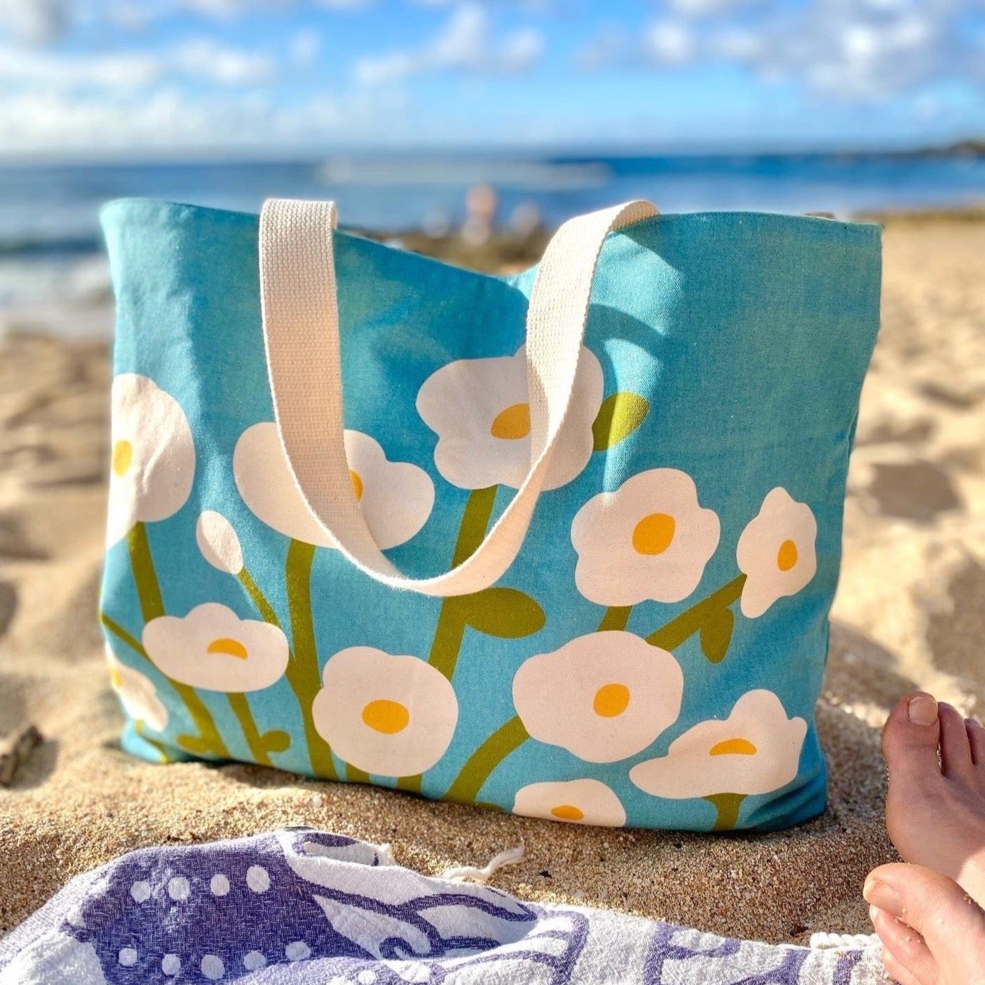 Big, sunny white and yellow flowers on this scandi-inspired beach bag with a sky blue background. 