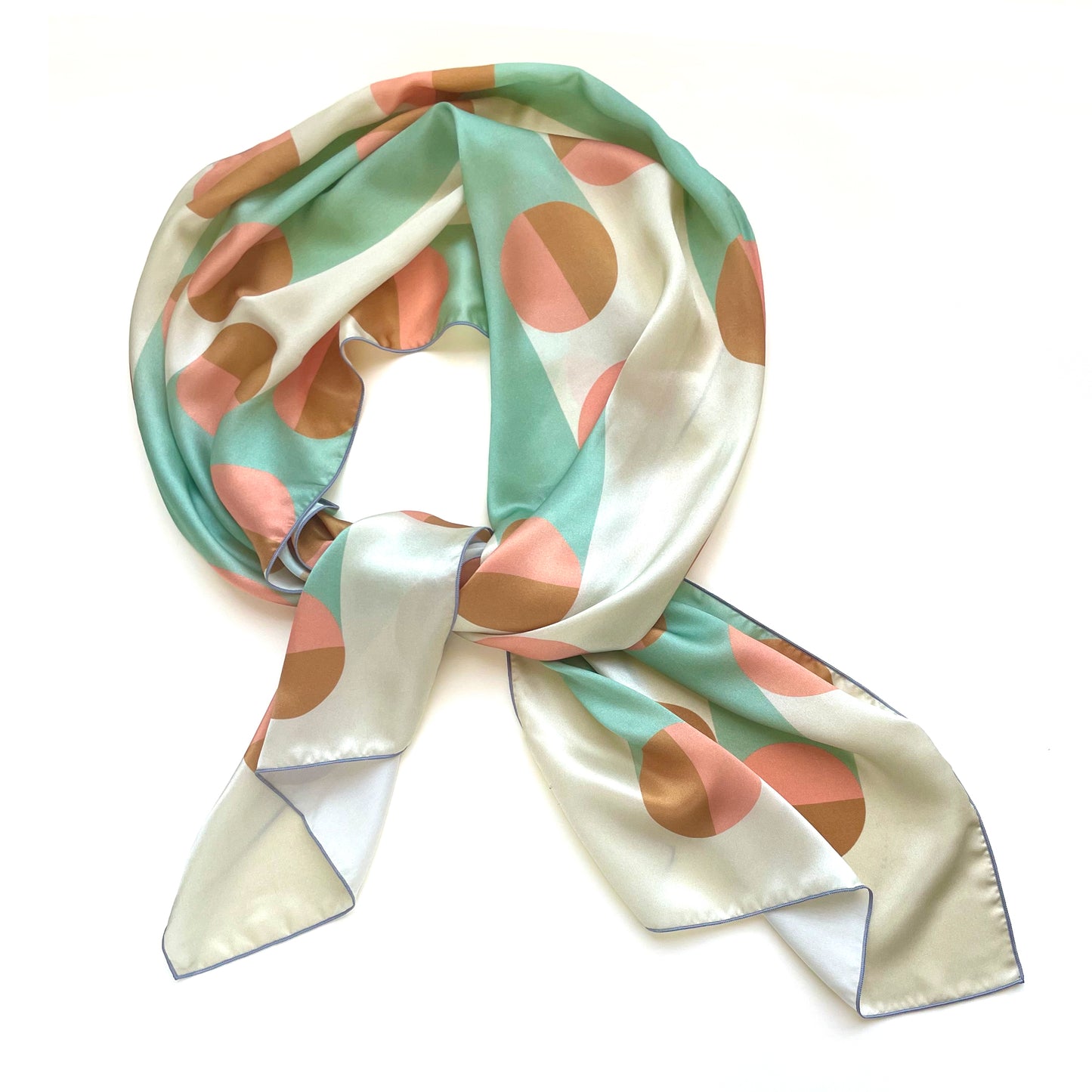Art deco inspired geometric print on a long silk scarf in subtle pastels: pink, grey, and gold.